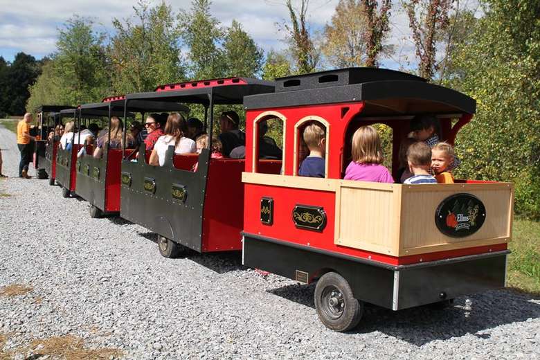 kids and their parents riding on a red and black miniature train