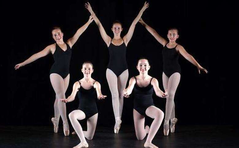 5 older girls standing with arms up and out