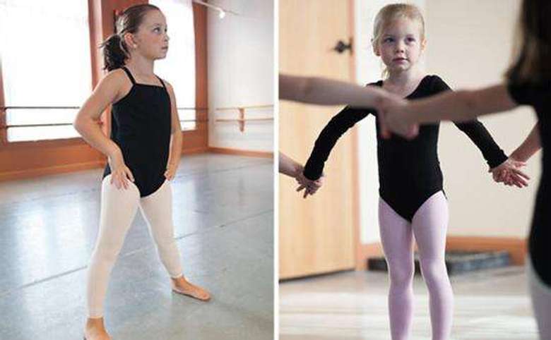 Two young girls standing listening to instruction
