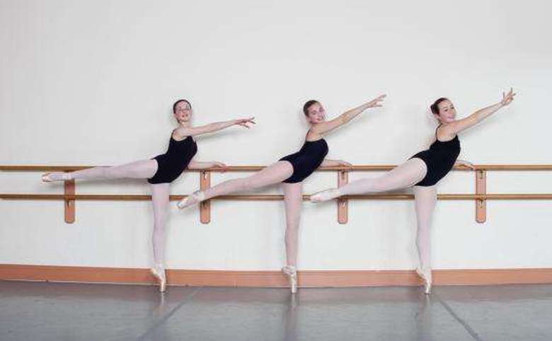 Three girls lined up along barre