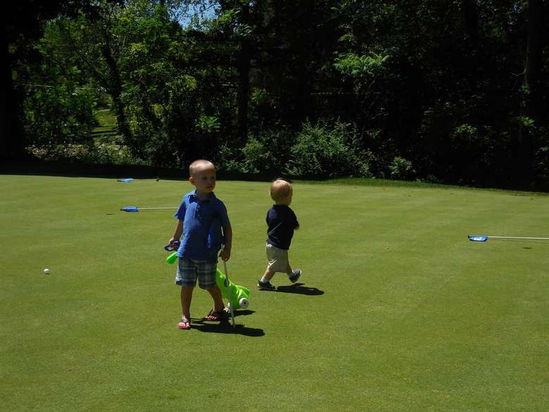 two young boys walking on a golf course