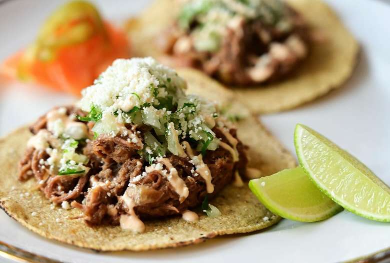 beef taco topped with lettuce and cheese, and there's two limes