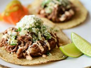 beef taco topped with lettuce and cheese, and there's two limes