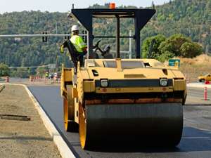 a paving construction vehicle and worker at the wheel