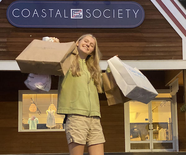 teen girl standing in front of French Commons in Lake George with shopping bags in her hands