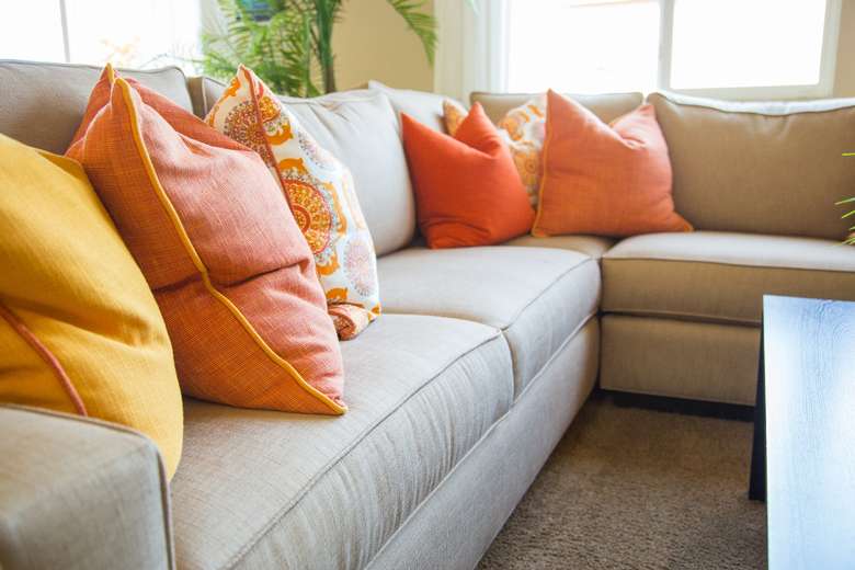 a beige couch with orange and yellow pillows