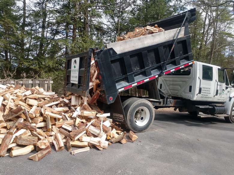 truck pouring firewood on ground