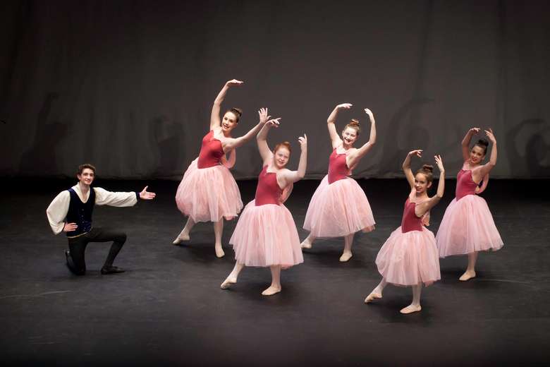Guy pointing towards 5 ballerinas