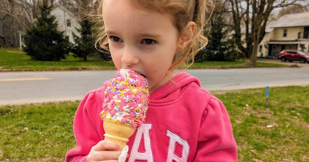 little girl eats ice cream with unicorn sprinkles