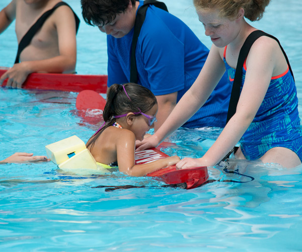 girl taking a swim lesson with a lifeguard
