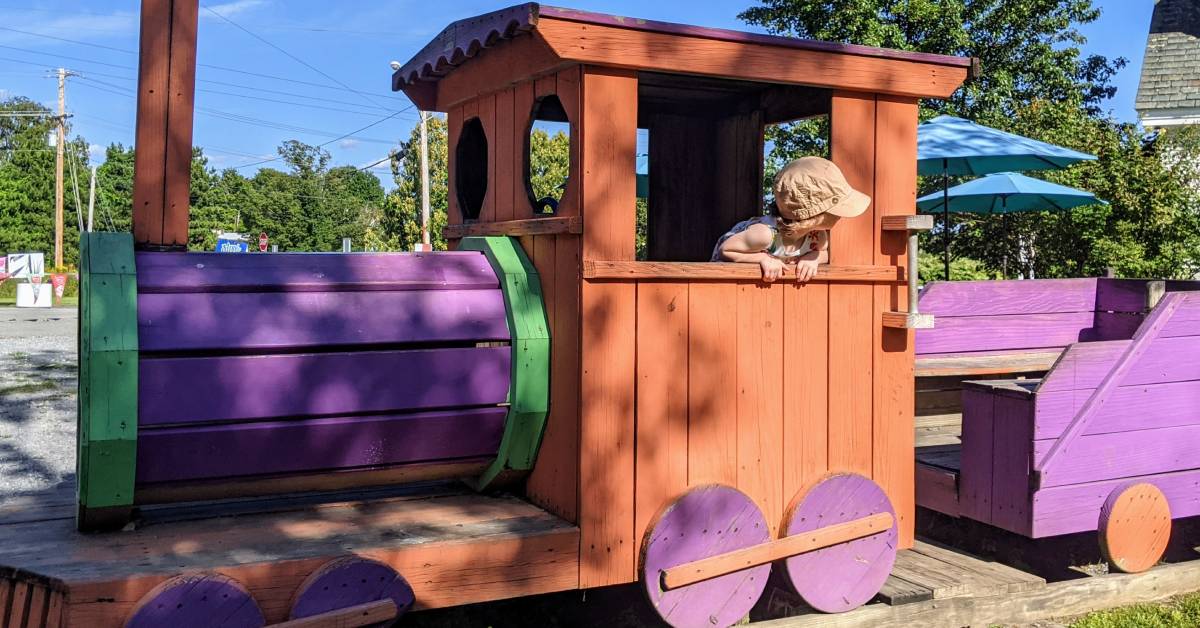 little girl on wooden train at sprinkles in queensbury