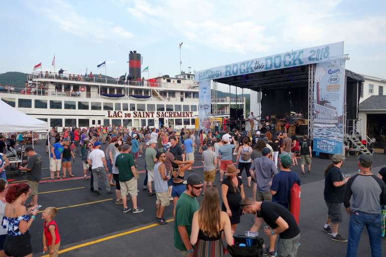 crowd of people at rock the dock music festival with large steamboat in the background