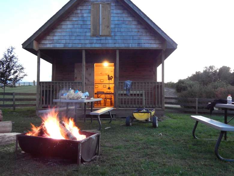 a cabin with a fire pit and tables outside