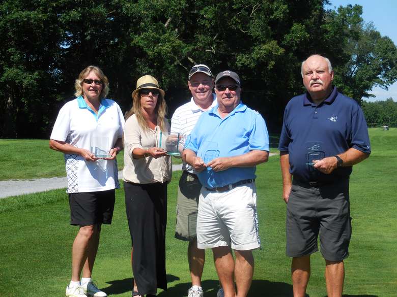 group of five golfers holding trophies