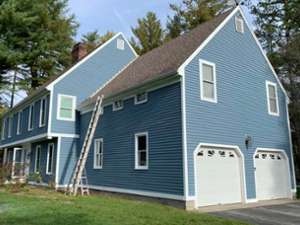 blue house with white window frames and two garage doors