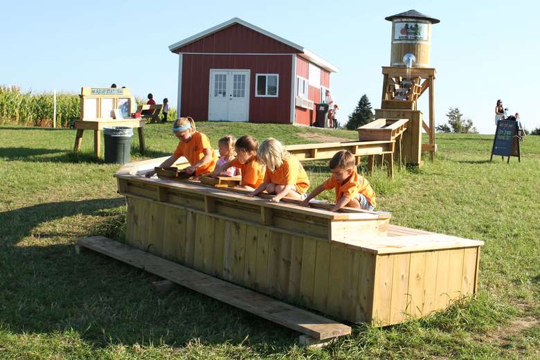 kids in orange shirts mining for gemstones in a trough