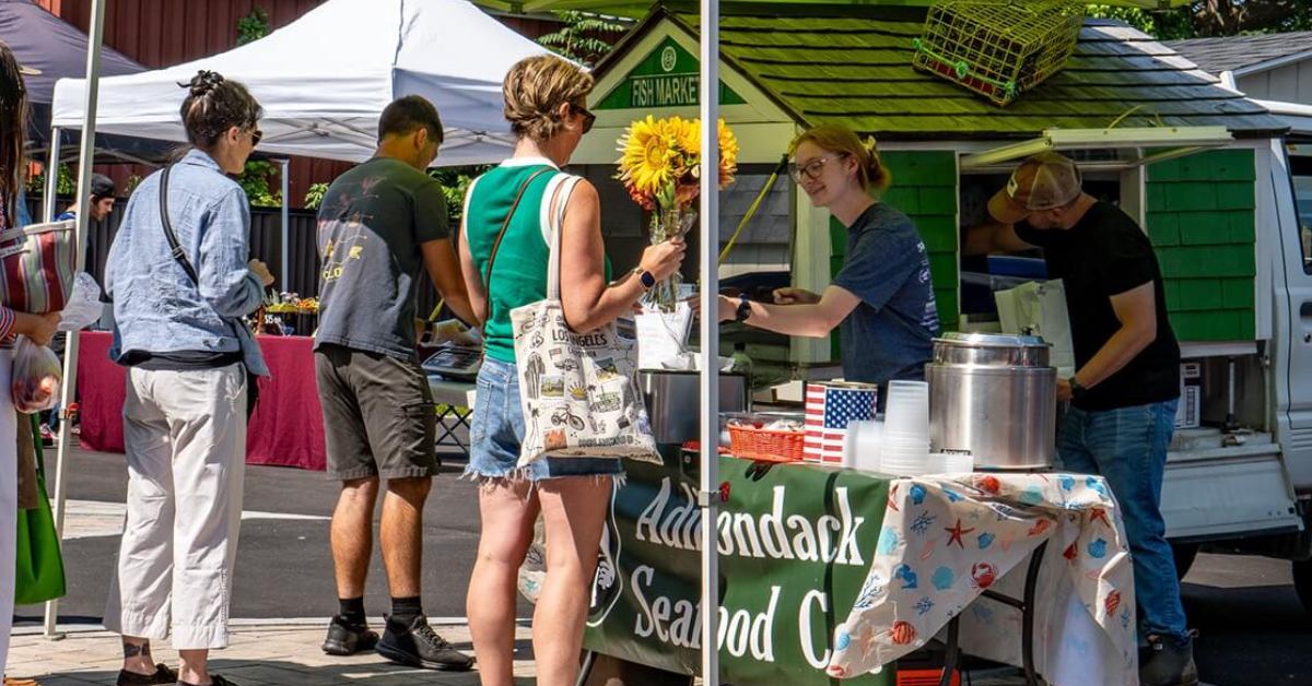 People in line at a tent being served seafood by workers