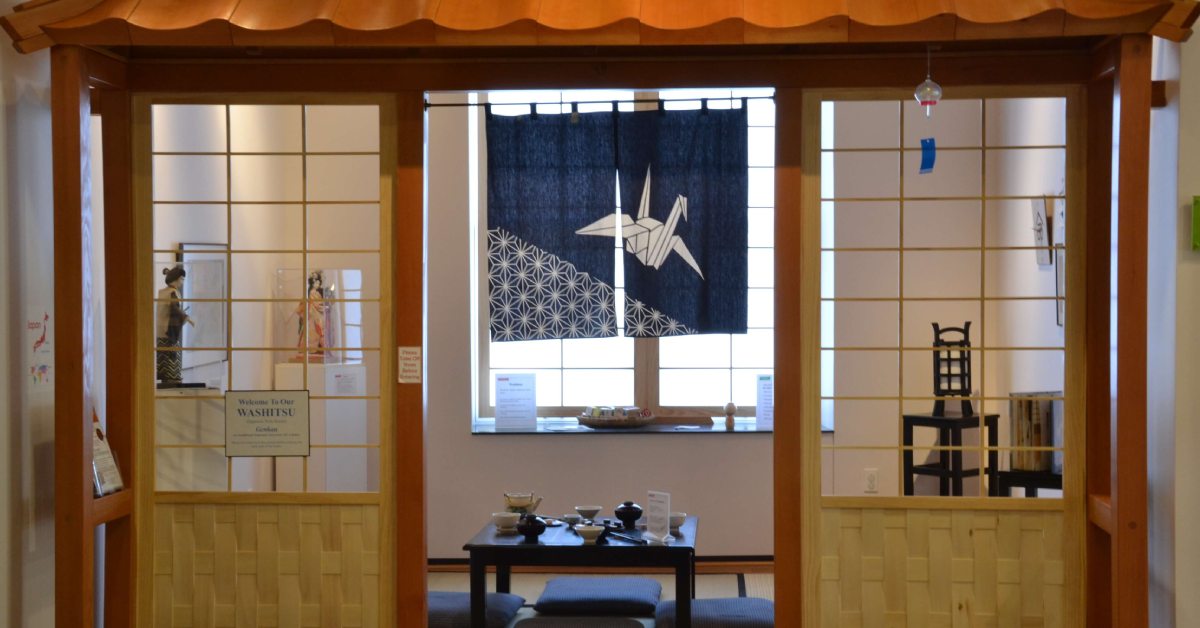 Two doors with an opening to a table with artwork and a blue art piece hanging over a window