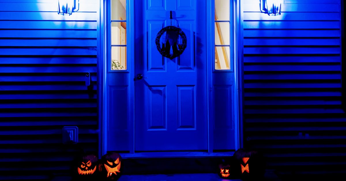 doorway to house decorated for halloween with mood lighting and jack o lanterns