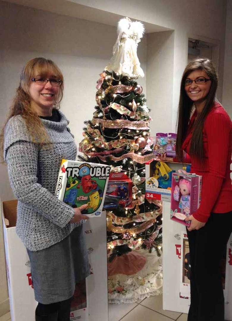 Women holding toys by Christmas tree