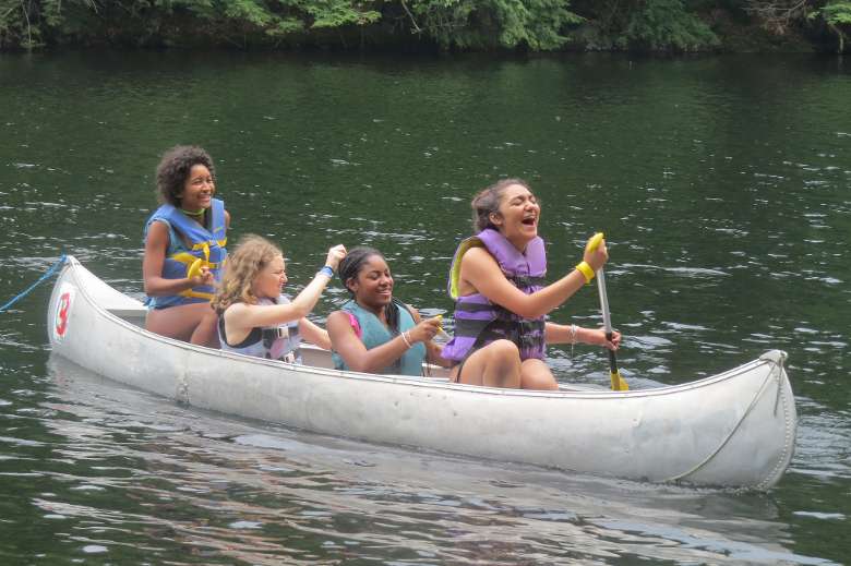 4 kids canoeing and laughing