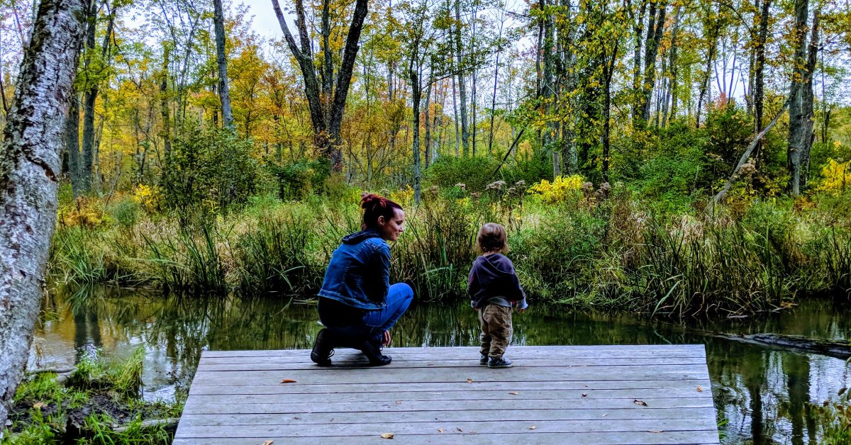 mom and kid at brook in nature preserve