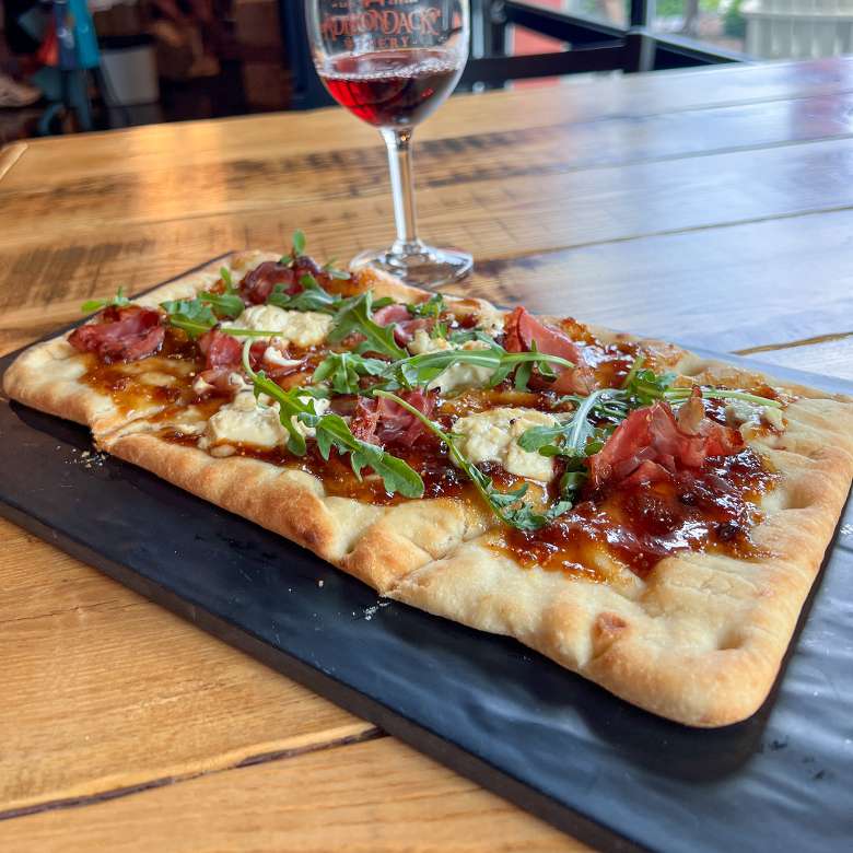 Give their delicious new flatbreads a try! flatbread pizza with glass of wine behind it