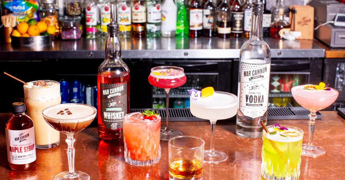 various different types of cocktails spread out on bar counter with war cannon spirits
